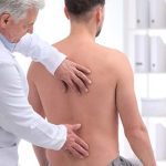 ACG-Chiropractor examining patient with back pain