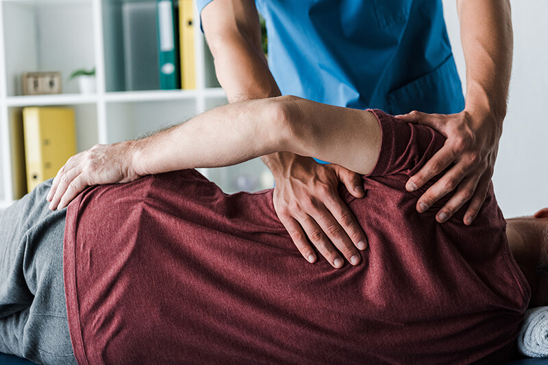 ACG doctor touching mature man lying on massage table