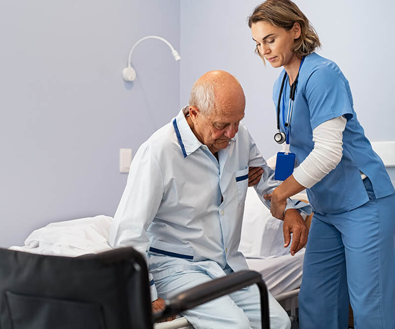 ACG nurse assisting senior man to get up from bed